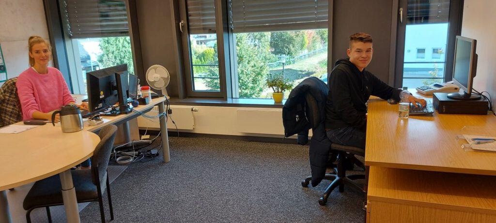 Schüler sitzt in einem Büro der Gemeinde an einem Schreibtisch.