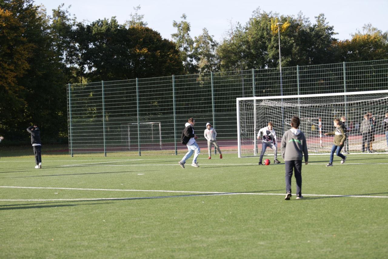 Schüler:innen spielen Fußball auf dem Schulhof